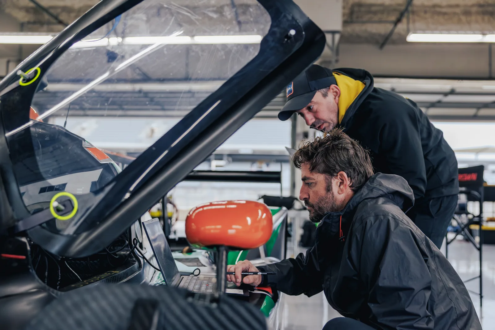 Two members of the team working together beside the race car’s cockpit at Circuit of the Americas