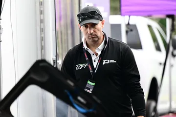 A Forbush Performance team member in a black cap and jacket beside the transporter at Road Atlanta.