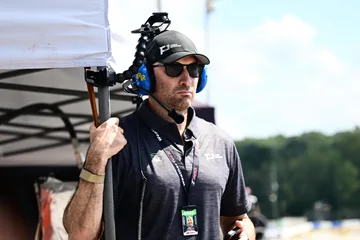 A Forbush Performance team member watches from the Road Atlanta pit wall wearing a radio headset.