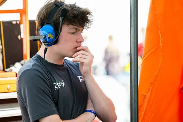 A young team member listens on a radio headset in the Road Atlanta paddock.