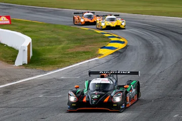 The No. 18 Duqueine leads two prototypes through a blue-and-yellow-curbed corner at Road Atlanta.