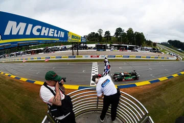 A marshal waves the checkered flag as the No. 18 Duqueine crosses the Road Atlanta finish line.