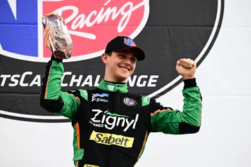 The Forbush Performance driver smiles and raises a trophy and fist on the Road Atlanta podium.