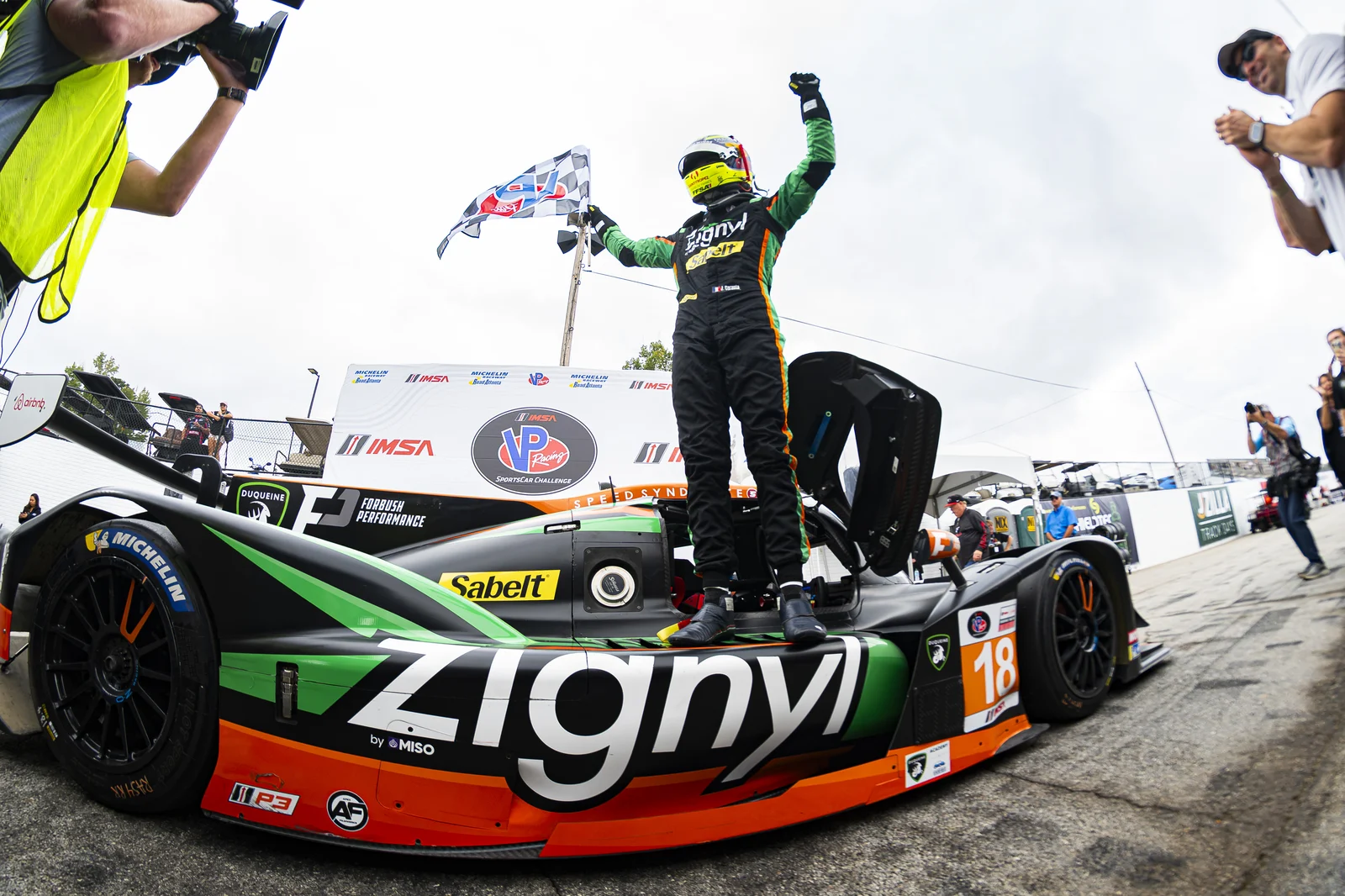 Jules Caranta celebrating atop the No. 18 with a checkered flag at Road Atlanta