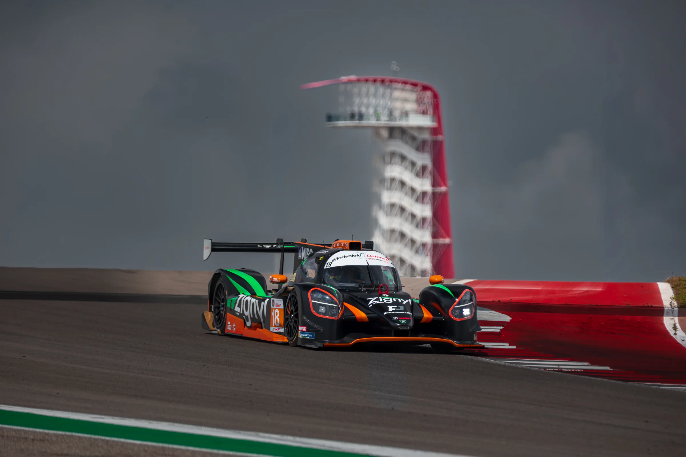 The No. 18 Duqueine racing past the COTA tower beneath a dramatic gray sky